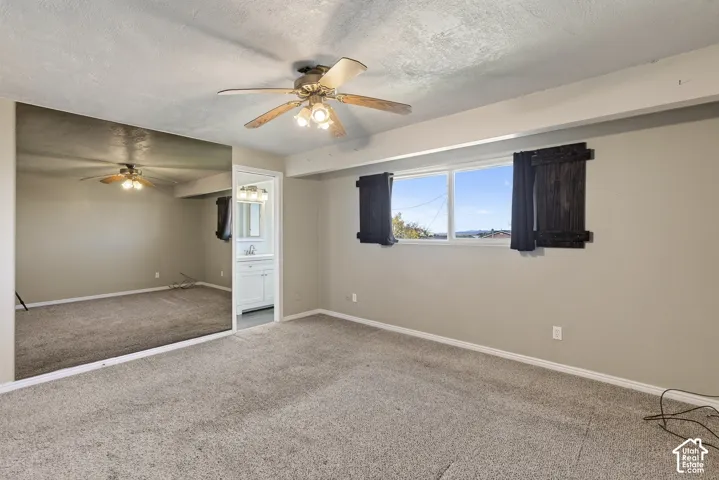 Room featuring wall-to-wall mirrored paneling, carpeting, dual-pane window, and a ceiling fan with integrated lighting