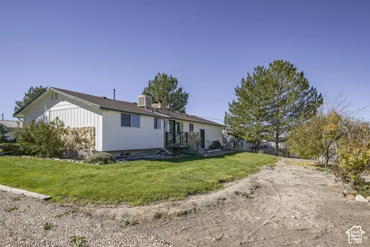 Single-story exterior with vertical siding, stone accent wall, multi-pitched roofline, and gravel driveway