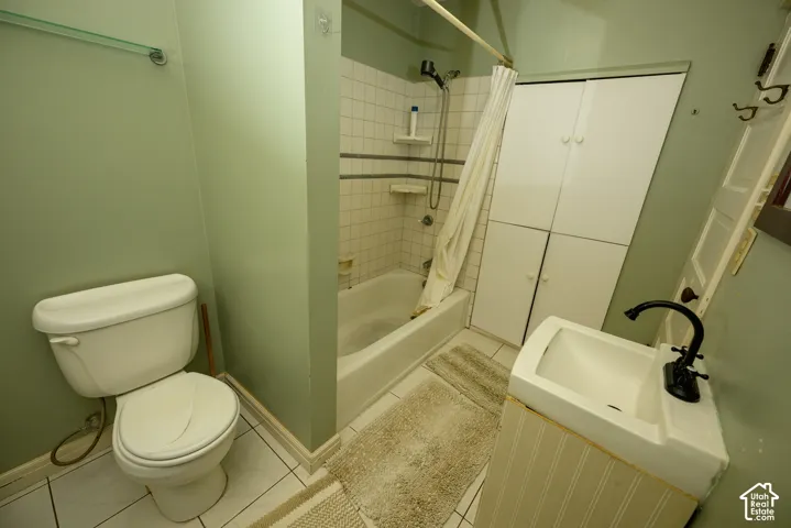 Bathroom featuring a tub-shower combination with ceramic tile surround, integrated floor-to-ceiling storage cabinetry, a pedestal sink with a matte black faucet, and white tile flooring