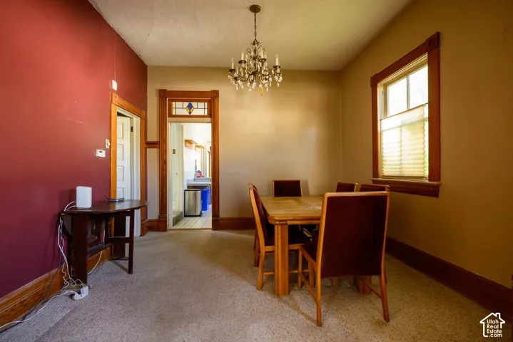 Interior space featuring ornate crystal chandelier, stained glass transom window, and original wood trim surrounding doorway and window frame