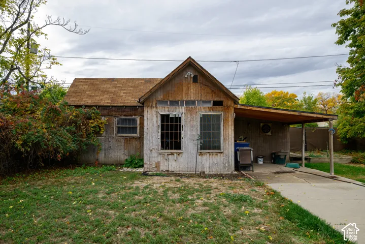 Single-story structure with wood siding, asphalt shingle roof, attached covered carport, and concrete driveway