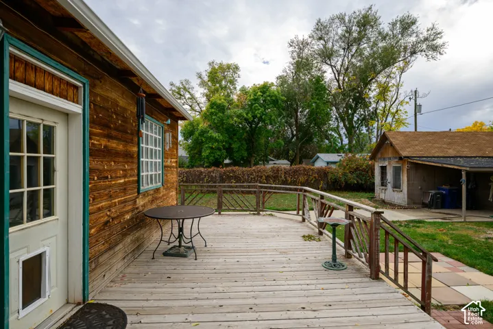 Wood-sided exterior with a glass-paneled door, expansive wooden deck with railing, and detached structure