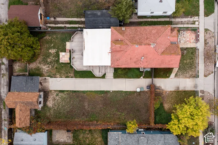Aerial perspective featuring a shingled roof, elevated wood deck, concrete driveway, detached storage structure, and fenced yard