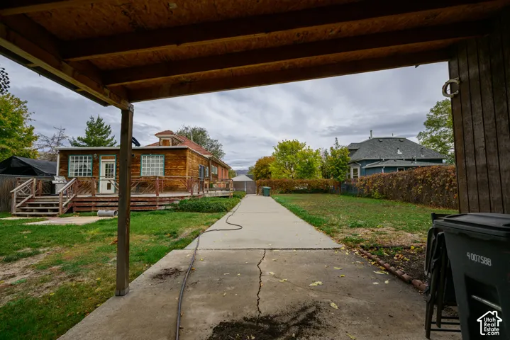 Exterior grounds featuring a covered patio, a concrete driveway, a wood-sided structure, and an attached wood deck