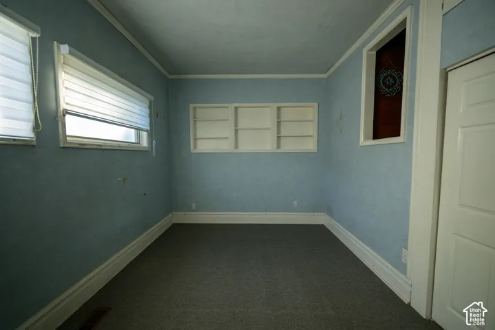 Room featuring inset wall shelving, recessed wall niche, dual windows with roller shades, and multi-panel interior door