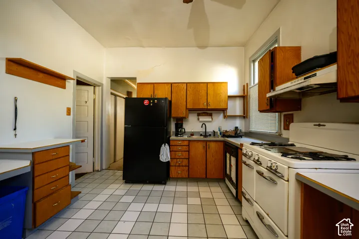 Kitchen featuring wood cabinetry, tiled flooring, built-in lower drawers, and wall-mounted shelving