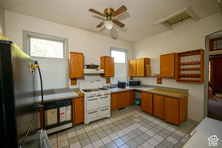 Kitchen featuring wood cabinetry, checkerboard tile flooring, natural light through dual windows, a ceiling fan, and built-in wine storage