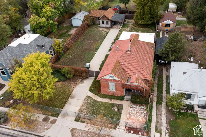 Brick exterior featuring a tile roof, covered front porch, concrete driveway, and detached rear structure