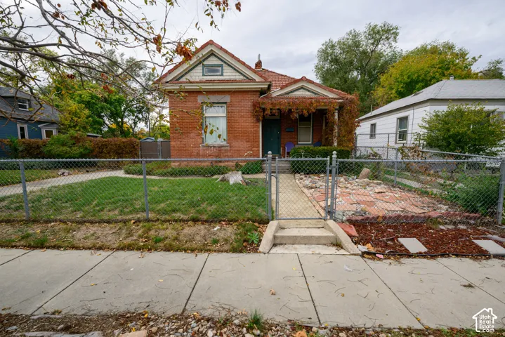 Red brick exterior featuring a tiled gable roof, covered front porch, and a concrete front walkway