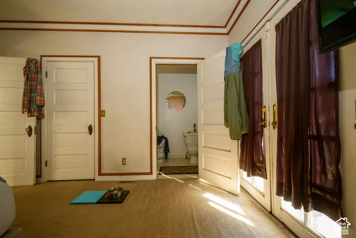 Interior space featuring multi-panel wood doors, decorative crown molding, and double glass-paneled doors with brass hardware