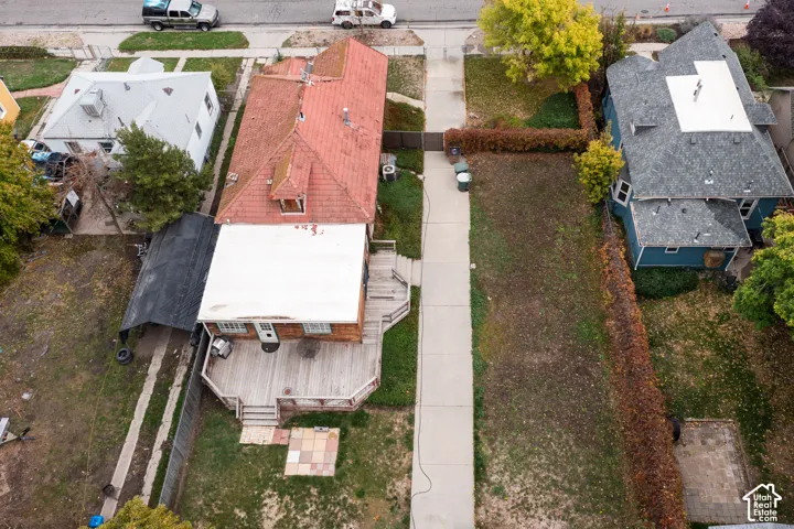 Aerial perspective featuring a multi-level wood deck, concrete driveway, stone paver patio, and detached metal carport structure