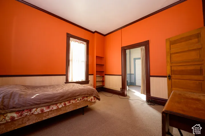 Interior space featuring natural wood-finish door, extensive wood-finish window and doorway trim, beadboard wainscoting, and built-in wall shelving