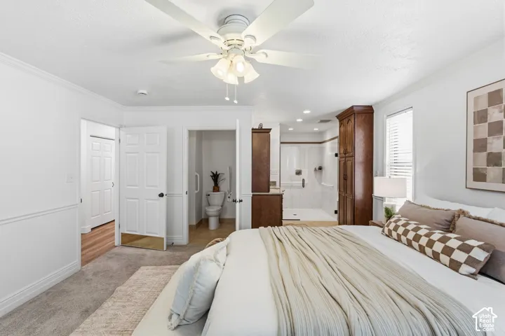 Neutral-toned carpeted flooring, white multi-panel interior doors, ceiling fan with integrated lighting, and a built-in floor-to-ceiling wooden storage cabinet