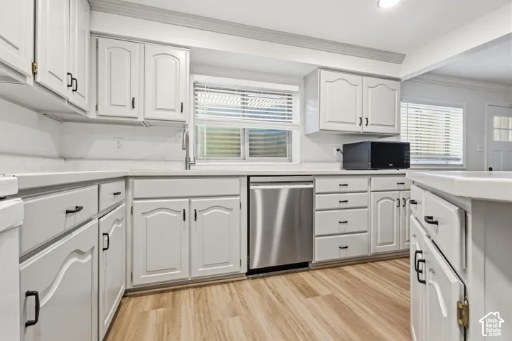 Kitchen featuring white cabinetry with matte black hardware, solid-surface countertops, wood-finish flooring, and a stainless steel dishwasher