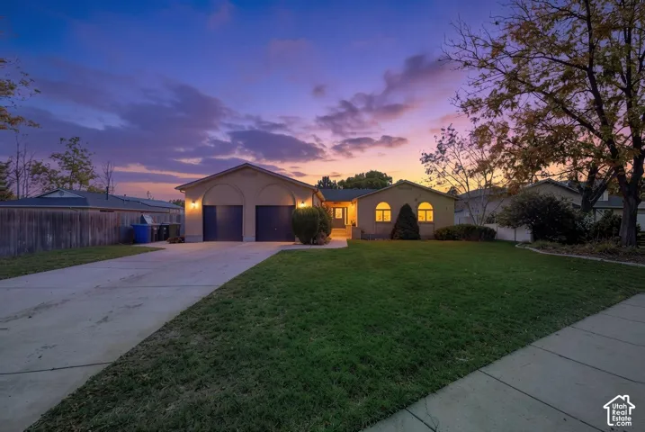 Single-story residence featuring a stucco exterior, an attached two-car garage with arched entryways, arched windows, and a landscaped front lawn