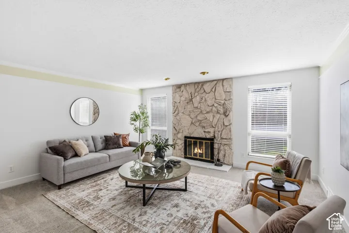 Living area featuring a floor-to-ceiling natural stone wood burning fireplace surround, neutral carpeting, and windows