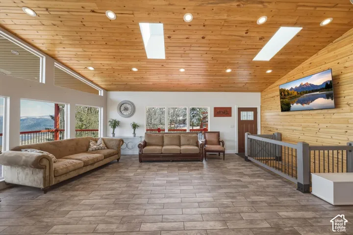 Vaulted wood-plank ceiling featuring recessed lighting and dual skylights, complemented by wood-paneled wall accents, tile flooring, and large windows