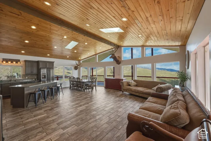 Vaulted wood-plank ceiling featuring recessed lighting and dual skylights, tile flooring, and expansive windows incorporating mountain scenery