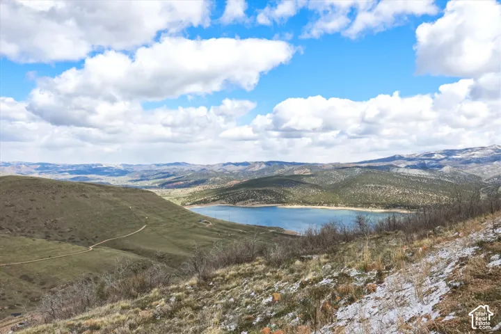 Expansive landscape featuring rolling hills, a reservoir, and distant mountain topography