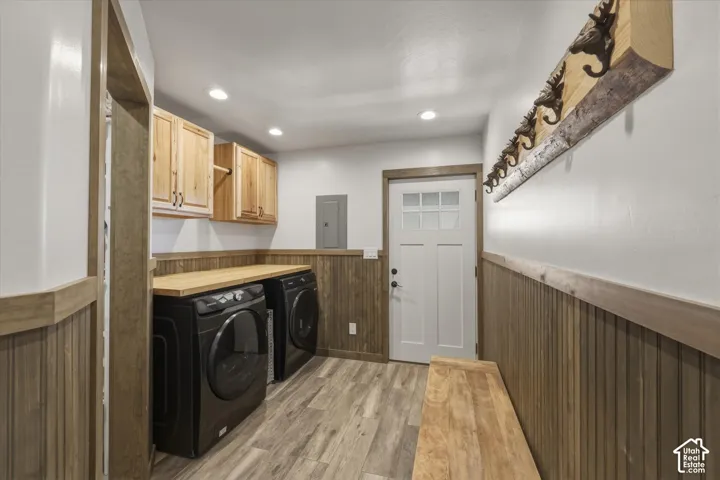 Laundry room featuring natural wood-finish cabinetry, a solid wood folding counter, wood-plank style flooring, vertical wood wainscoting, and a multi-panel exterior door with glass detailing