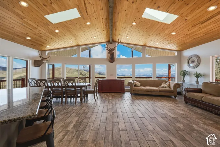Vaulted ceiling with tongue-and-groove wood paneling, dual skylights, recessed lighting, expansive windows, and wood-finish tile flooring