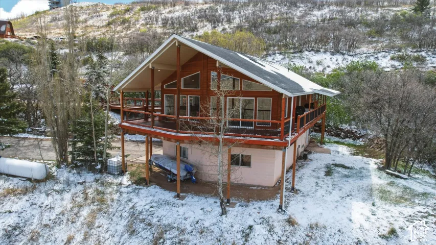 Multi-level exterior featuring cedar siding, a wraparound wood deck with metal railings, gabled rooflines, and expansive windows