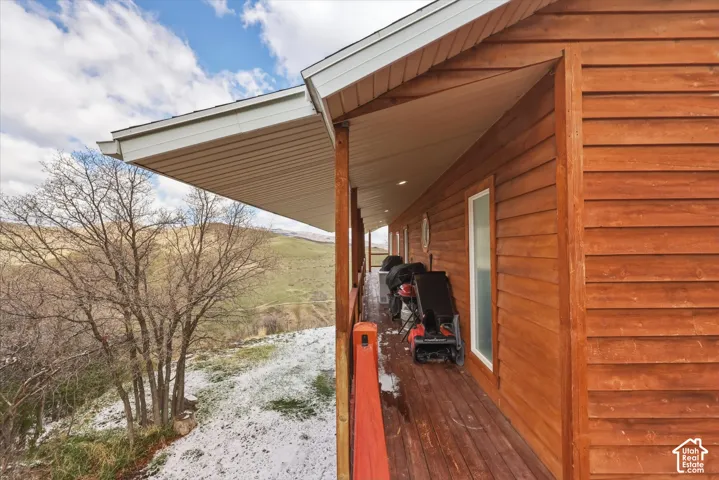 Covered wrap-around deck featuring wood siding, recessed lighting, and a stained wood-plank floor