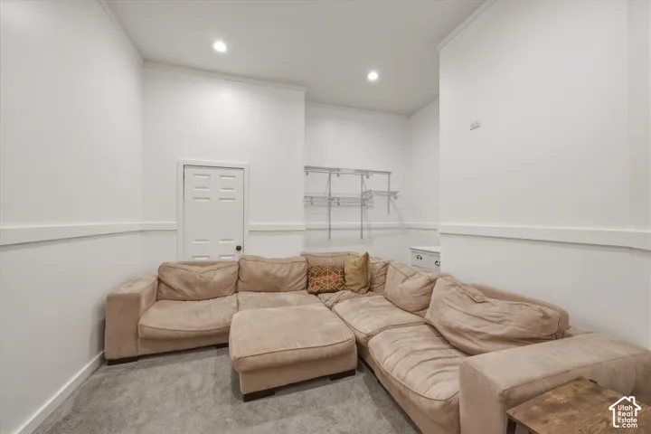 Neutral interior space featuring high ceilings, recessed lighting, white wall paneling, carpeting, and integrated metal shelving