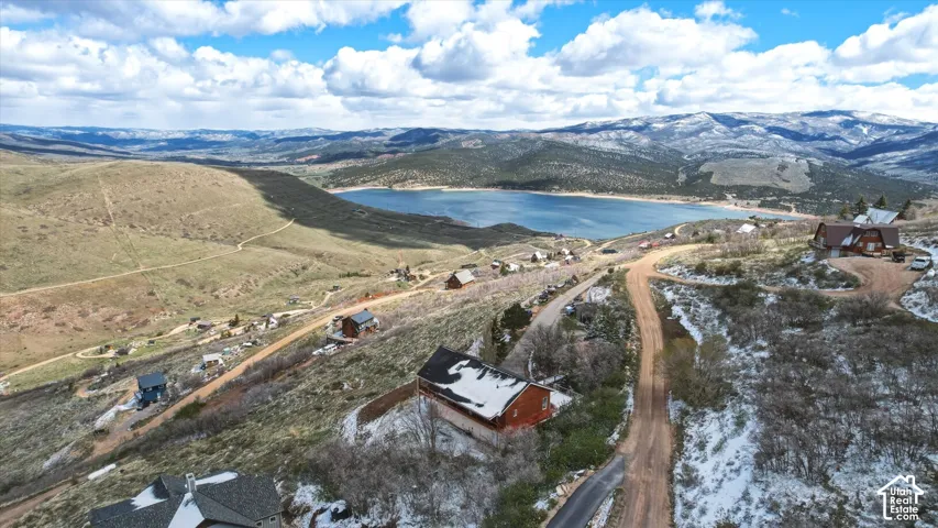 Aerial perspective featuring mountain terrain, a large reservoir, and sloping landscape