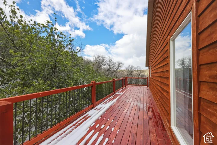 Elevated wood deck featuring horizontal wood siding, iron balusters, and extensive wooden plank flooring