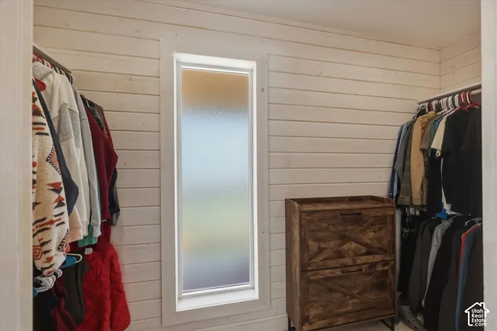 Storage space featuring horizontal light-toned wood-plank walls and a vertical window with frosted glass