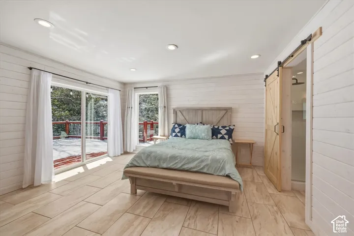 Horizontal white plank wall paneling, tile flooring, recessed lighting, and a sliding wood barn door