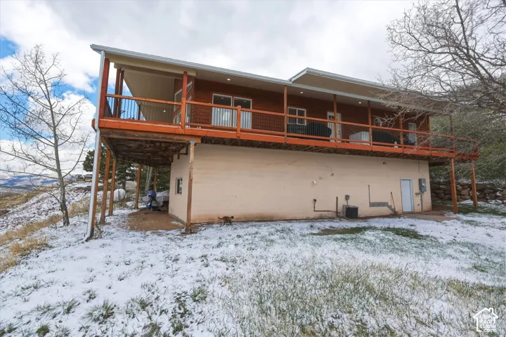 Exterior elevation featuring horizontal wood siding, an elevated wrap-around deck with metal railings, and recessed soffit lighting