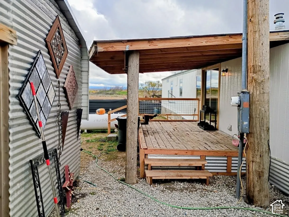 Covered wood deck featuring a post-and-beam structure, wire-mesh railing, and wood-step entry