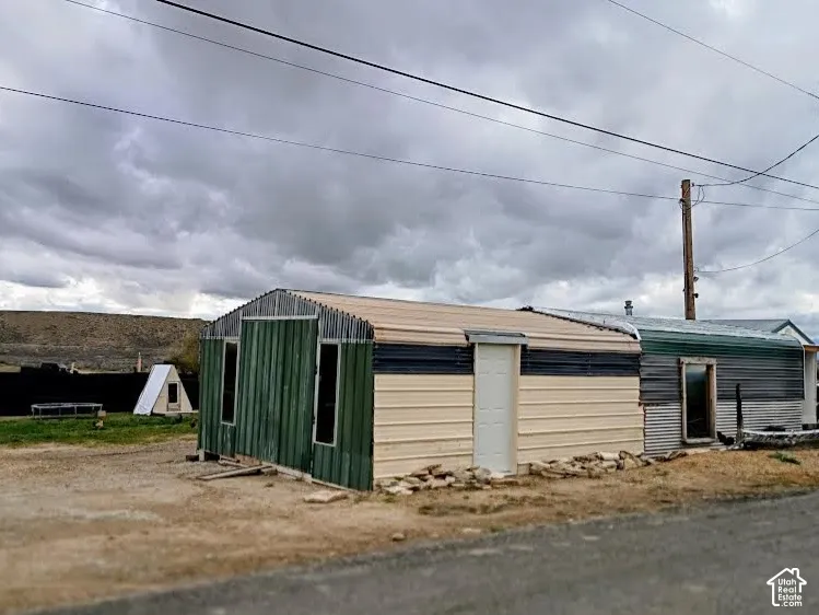 Exterior structure featuring corrugated metal siding, a dual-tone finish, and a solid-core entry door