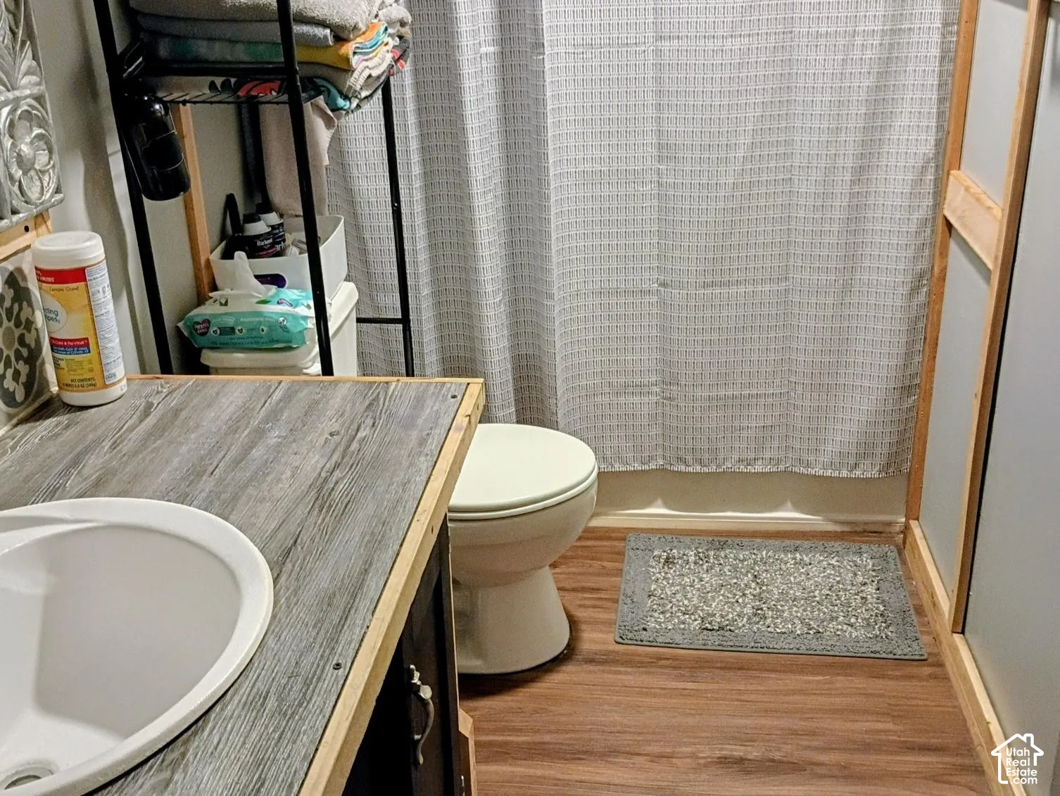 Bathroom featuring a vanity with a wood-finish countertop, white drop-in basin, and wood-finish flooring