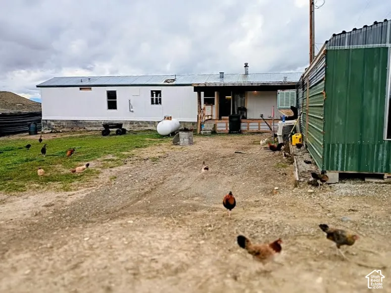 Exterior featuring a metal-sided dwelling, corrugated metal roofing, an outdoor propane tank, and a metal utility structure