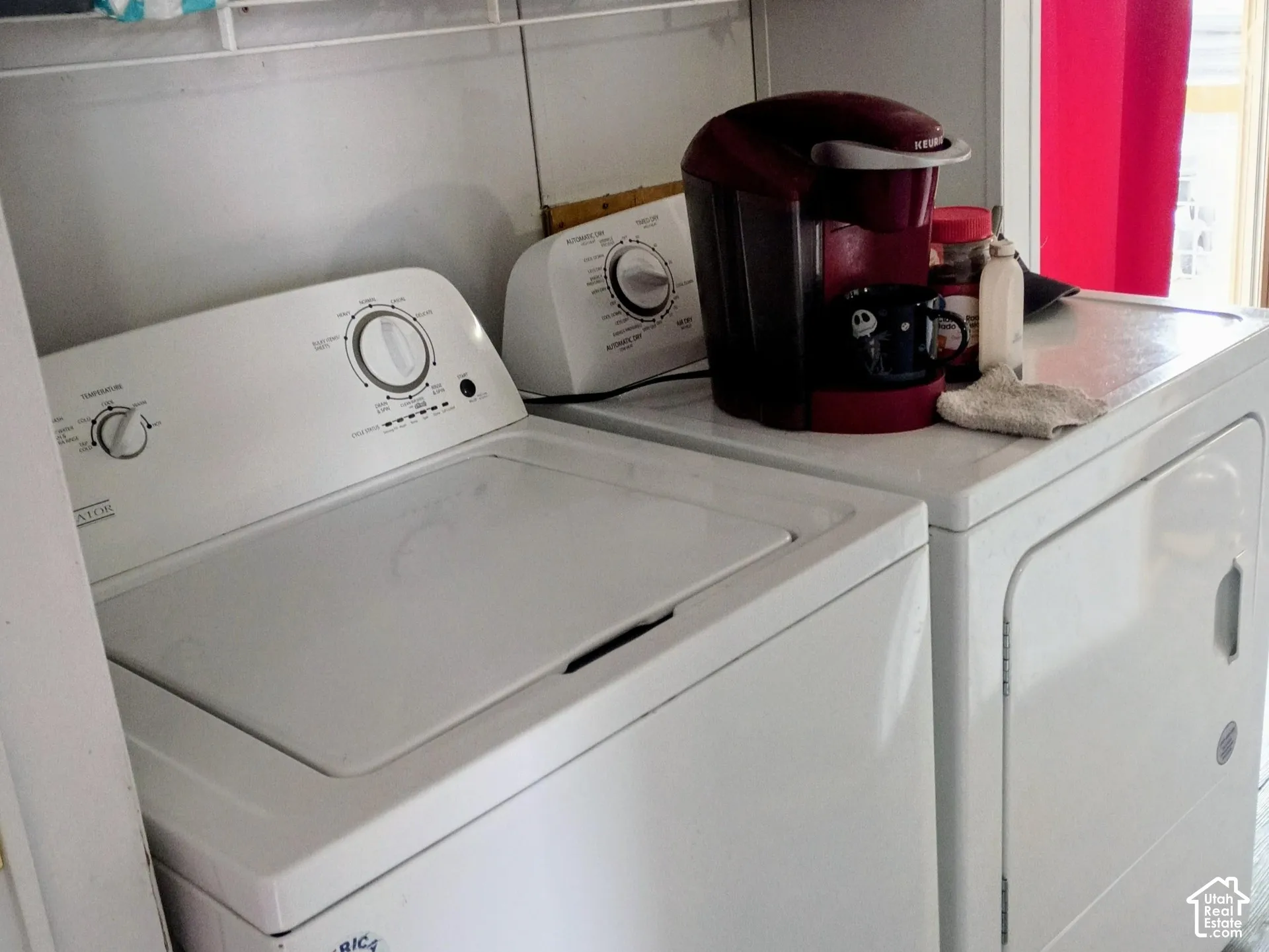 Laundry area featuring white top-loading washer and front-loading dryer, metal wire shelving, and wood-finish flooring