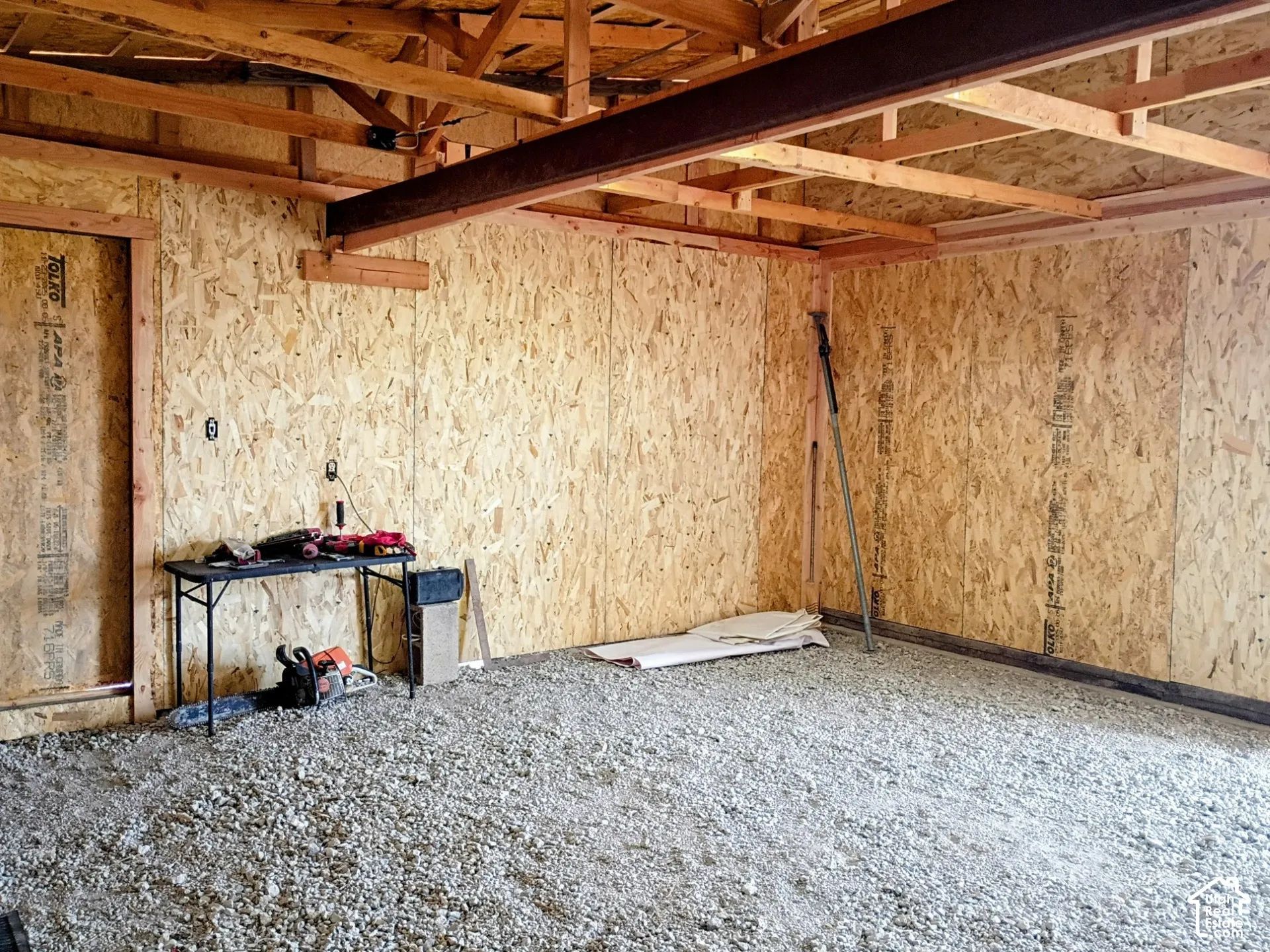 Structural framework featuring exposed wooden rafters, oriented strand board wall paneling, and an exposed steel support beam