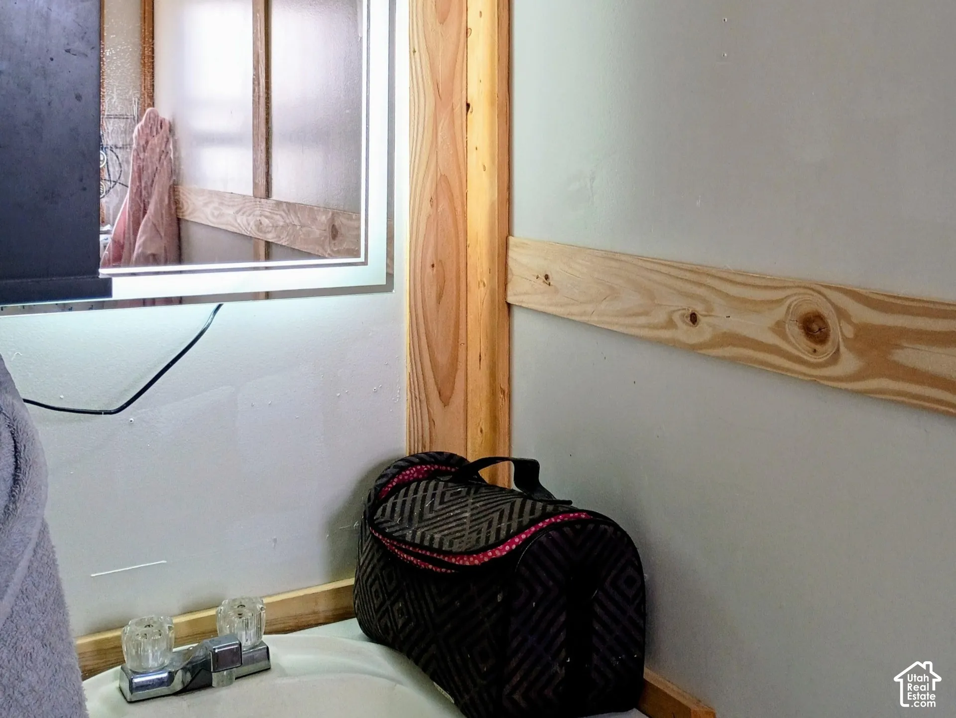 Wall-mounted LED-backlit mirror featuring a rectangular frame, complemented by natural wood-finish trim and paneling accents