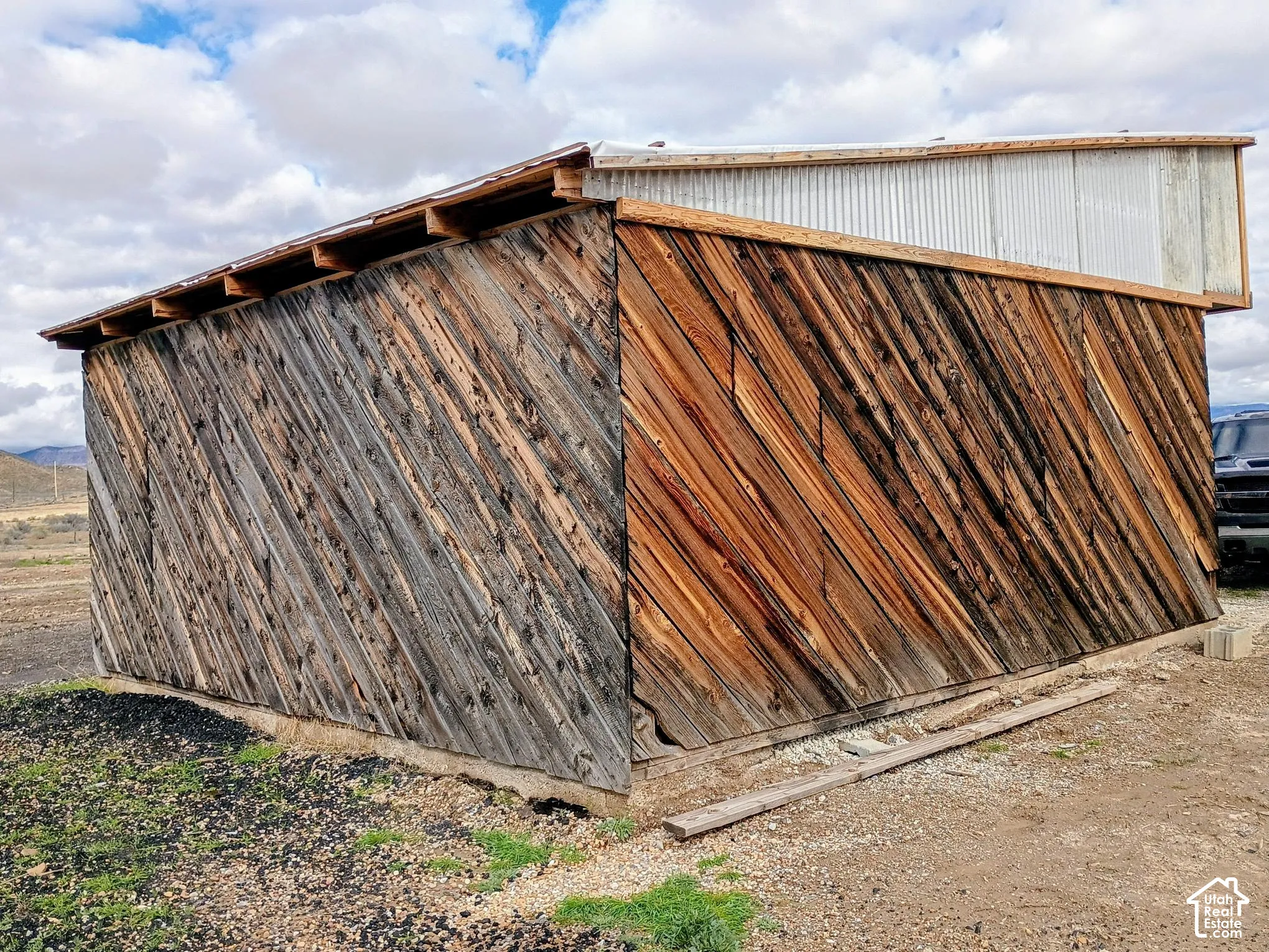 Outbuilding featuring diagonal wood siding and a corrugated metal roof