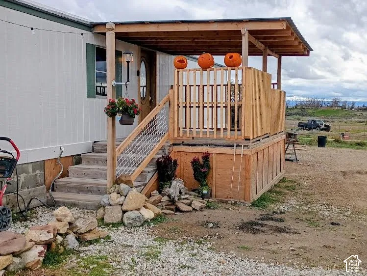 Covered exterior deck featuring wood construction, vertical slat railing, wire mesh stair balusters, and a wall-mounted outdoor light fixture