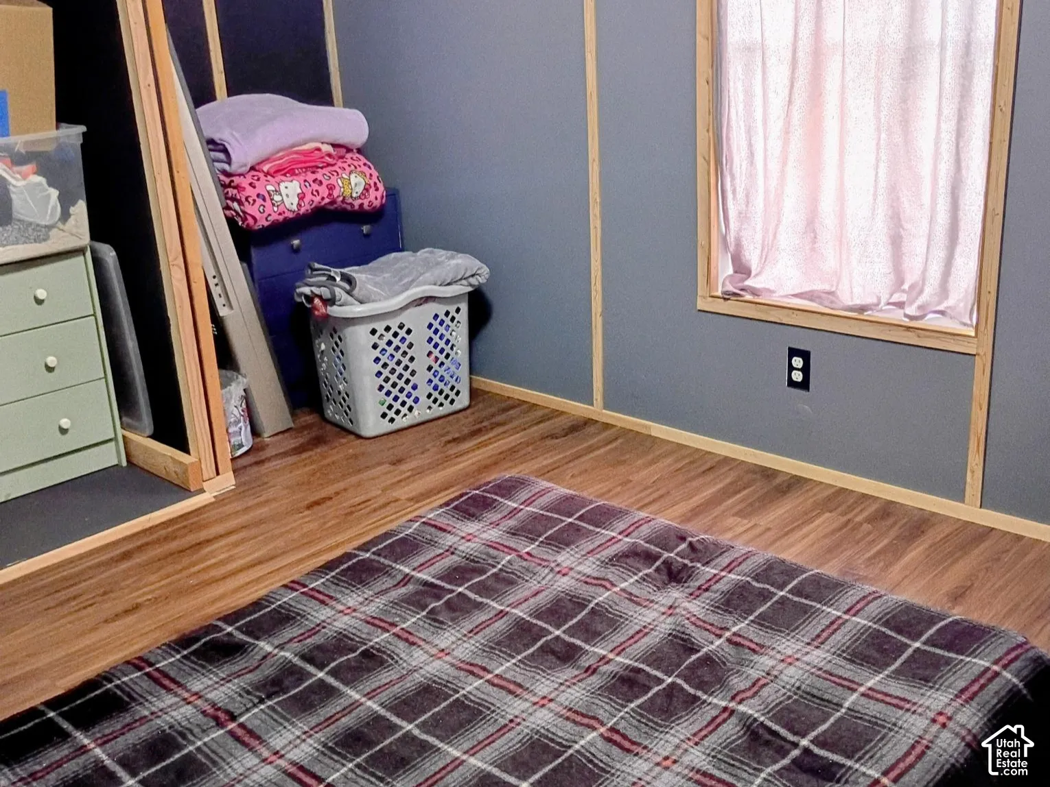 Wood-finish flooring, wood-trimmed window casing, and paneled walls with natural wood-tone battens