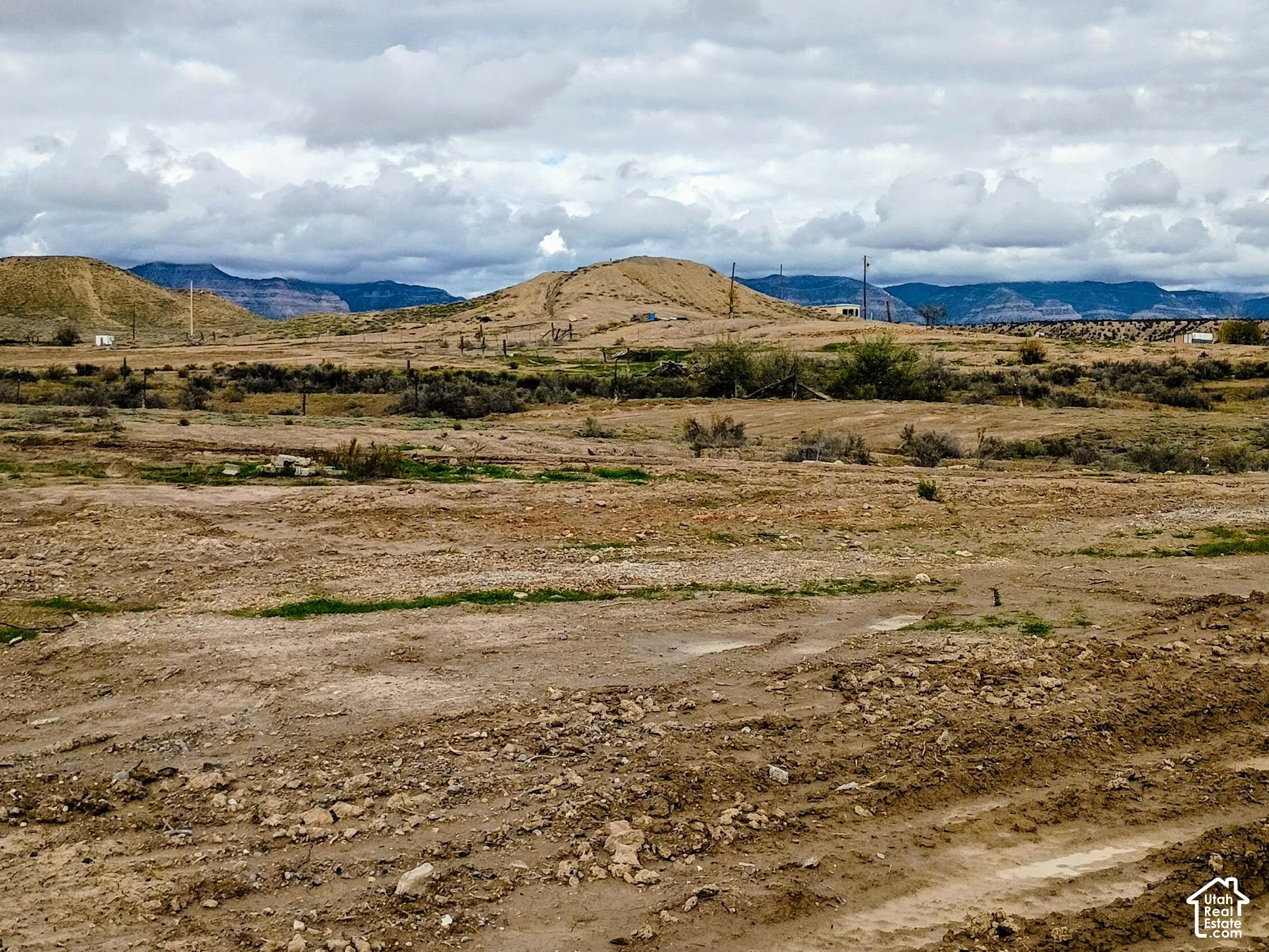 Expansive desert landscape featuring arid terrain, native shrubbery, and prominent mountain backdrops