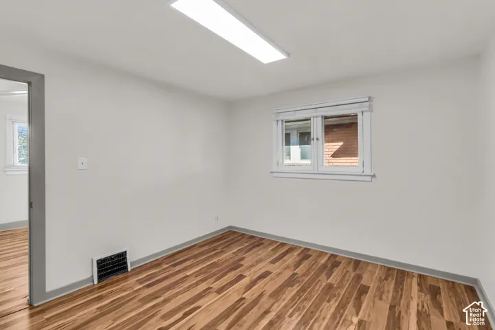 Room featuring wood-finish flooring, white walls, double-pane windows with casing, and integrated rectangular flush-mount lighting