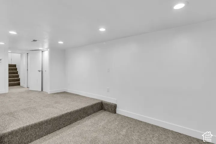 Finished interior space featuring neutral carpeting, recessed ceiling lighting, a multi-level floor plan, and paneled closet doors