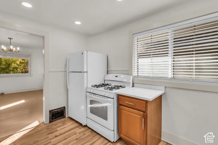 Kitchen featuring wood-finish flooring, white gas range, top-freezer refrigerator, wooden cabinetry with a white countertop, and recessed ceiling lighting