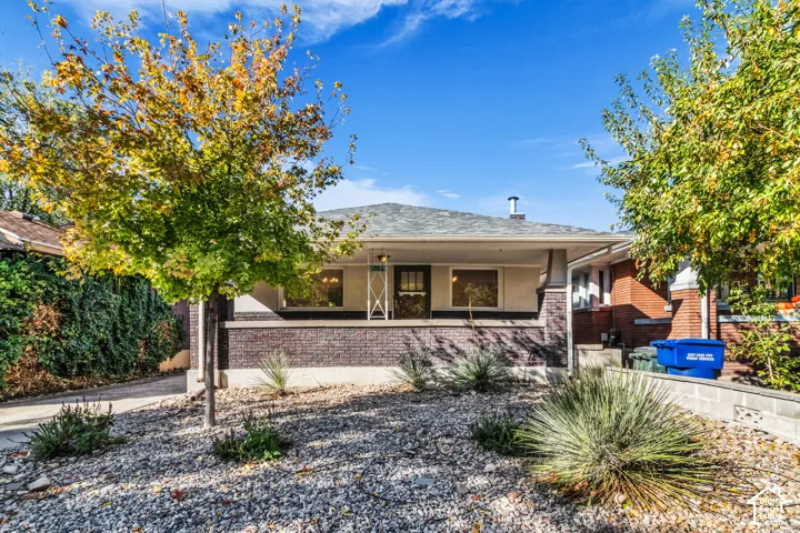 Bungalow exterior featuring a low-pitched roof, brick facade, covered front porch, and rock-covered landscaping