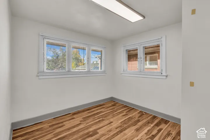 Room with wood-finish flooring, white walls, dual windows, and recessed ceiling lighting
