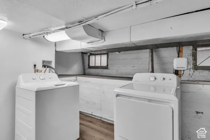 Laundry area featuring white-painted masonry walls, wood-finish flooring, and recessed ceiling lighting